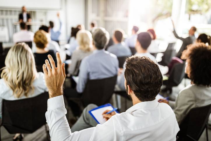 Mężczyzna podnoszący rękę na seminarium